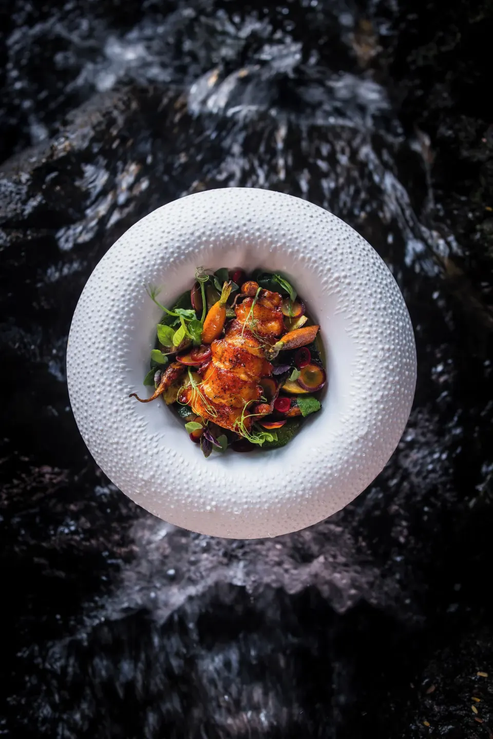 Plated seafood dish over flowing water at Hotel Wailea.