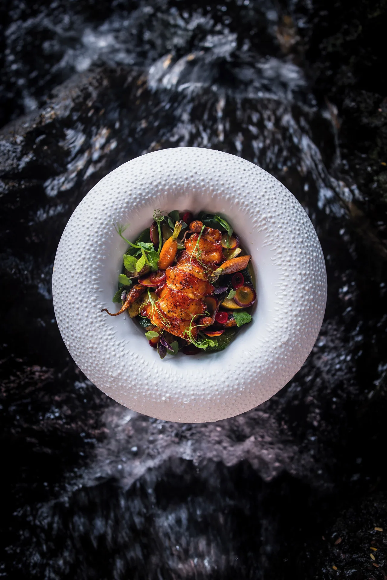 Plated seafood dish over flowing water at Hotel Wailea.