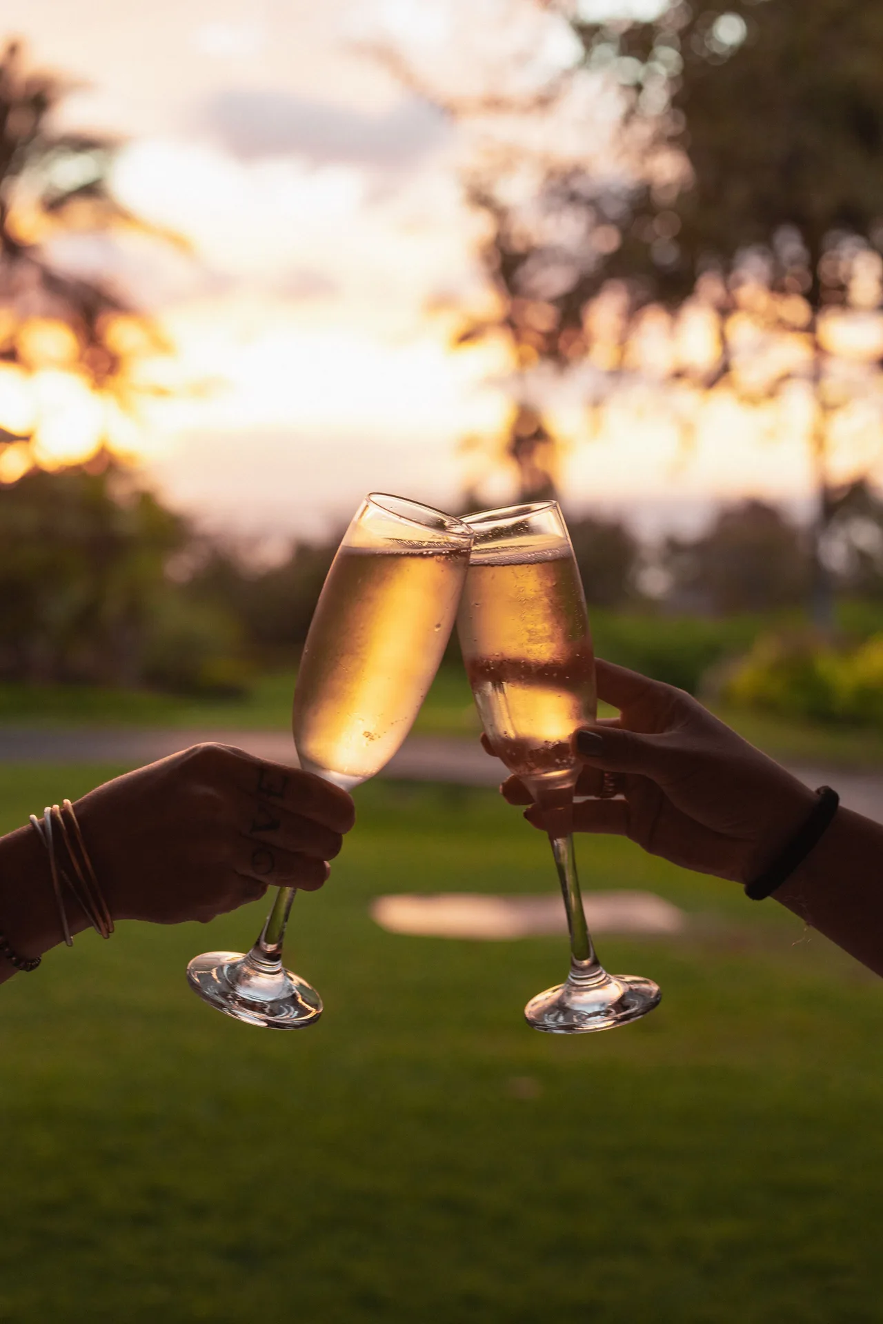 Two sparkling wine glasses toast at sunset on the grounds of Hotel Wailea.