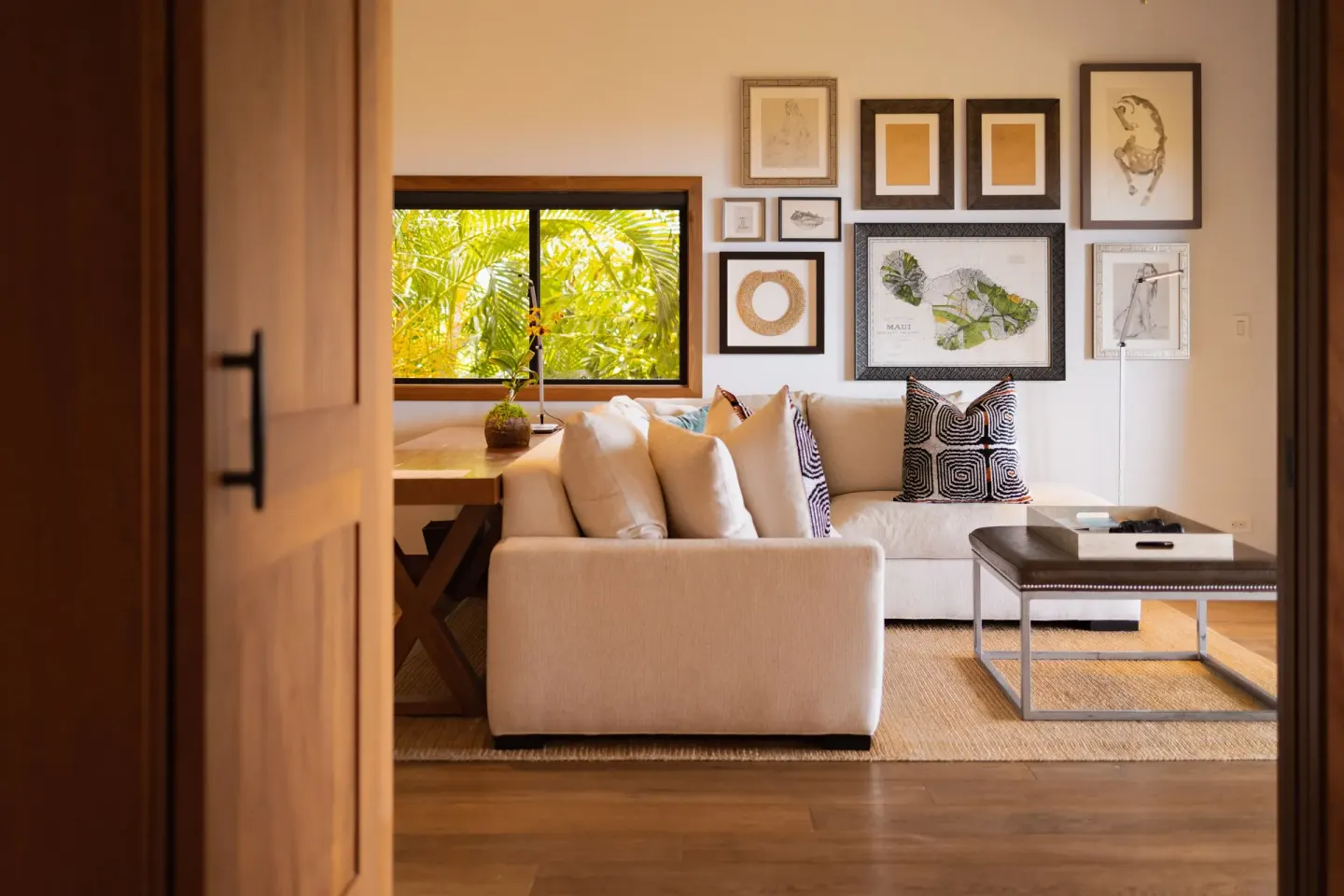 Ocean View Suite sitting room with sofa, art wall, and garden-facing window at Hotel Wailea.