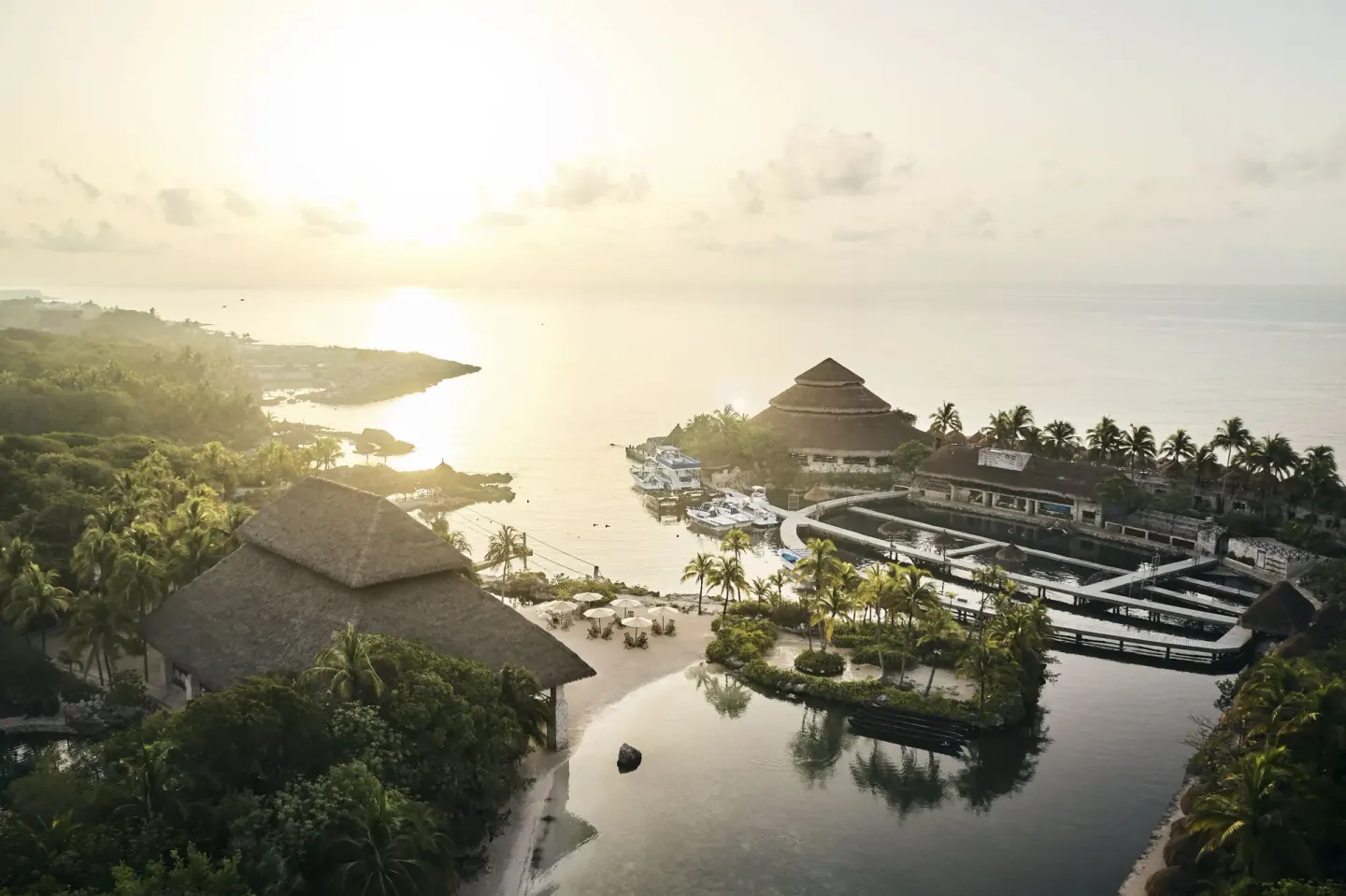 Aerial sunrise view of lagoons, palapa roofs, and ocean at Hotel Xcaret Arte.
