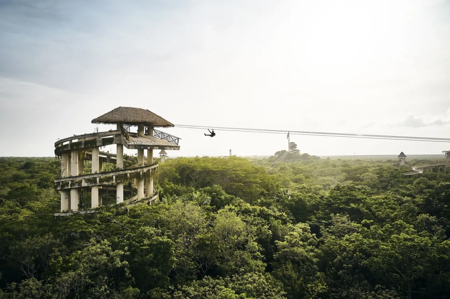 Zipline rider crossing above jungle near Hotel Xcaret Arte.
