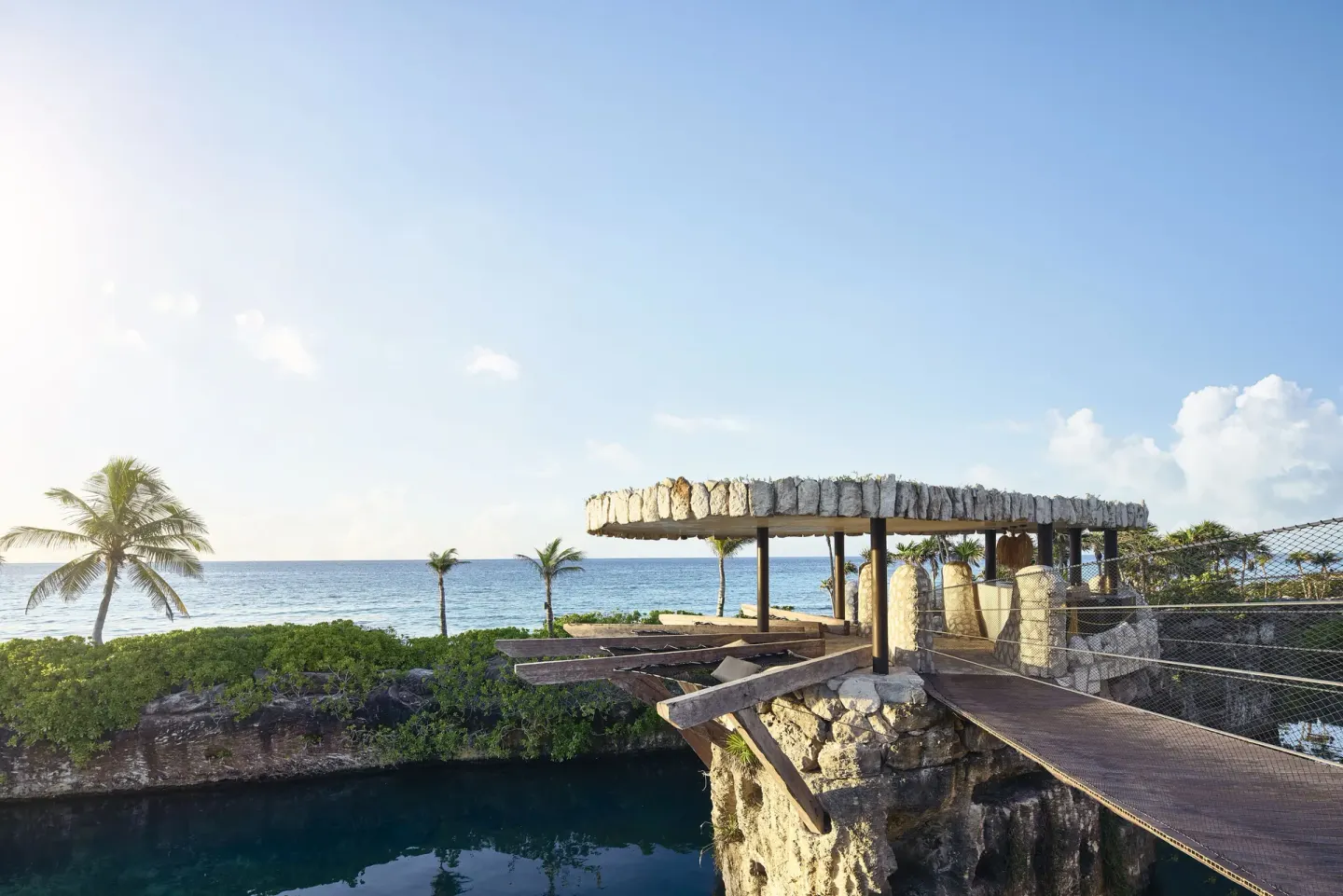 Oceanfront wooden bridge and rocky pavilion at Hotel Xcaret Arte.