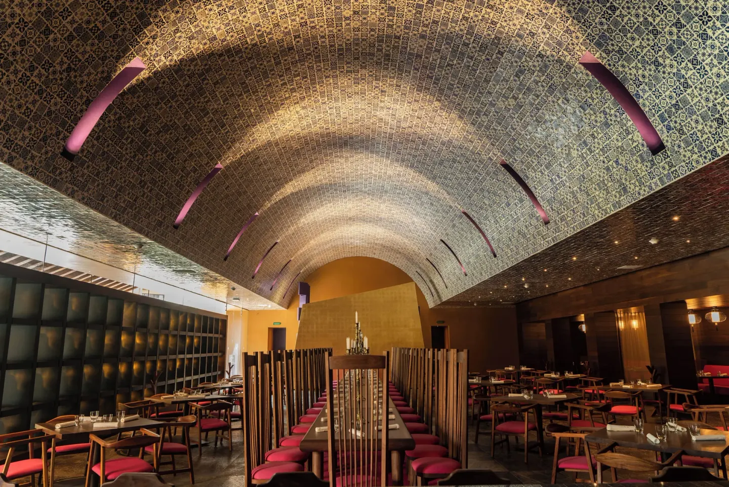 Arched restaurant dining room with red stools and patterned tile at Hotel Xcaret Arte.