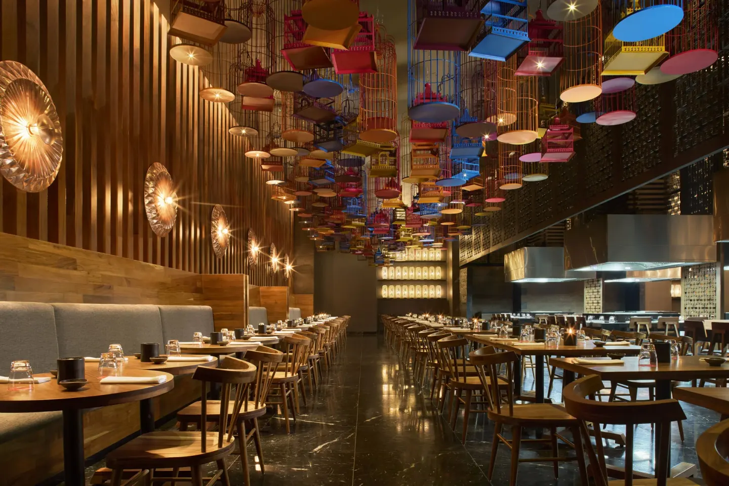 Restaurant dining room with hanging birdcages and an open kitchen at Hotel Xcaret Arte.
