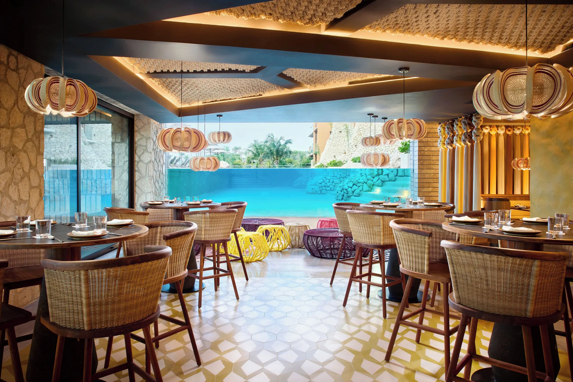 Restaurant with wicker chairs and turquoise water view at Hotel Xcaret Arte.