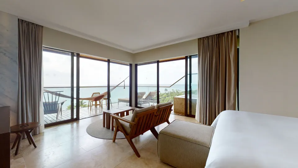 Junior Suite Oceanfront sitting area and terrace at Hotel Xcaret Arte with ocean beyond the glass doors.