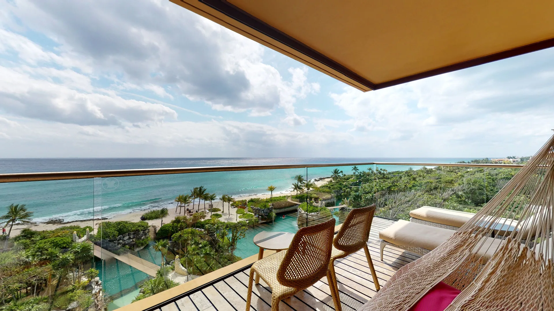 Junior Suite Oceanfront terrace at Hotel Xcaret Arte with hammock, chairs, and Caribbean Sea view.