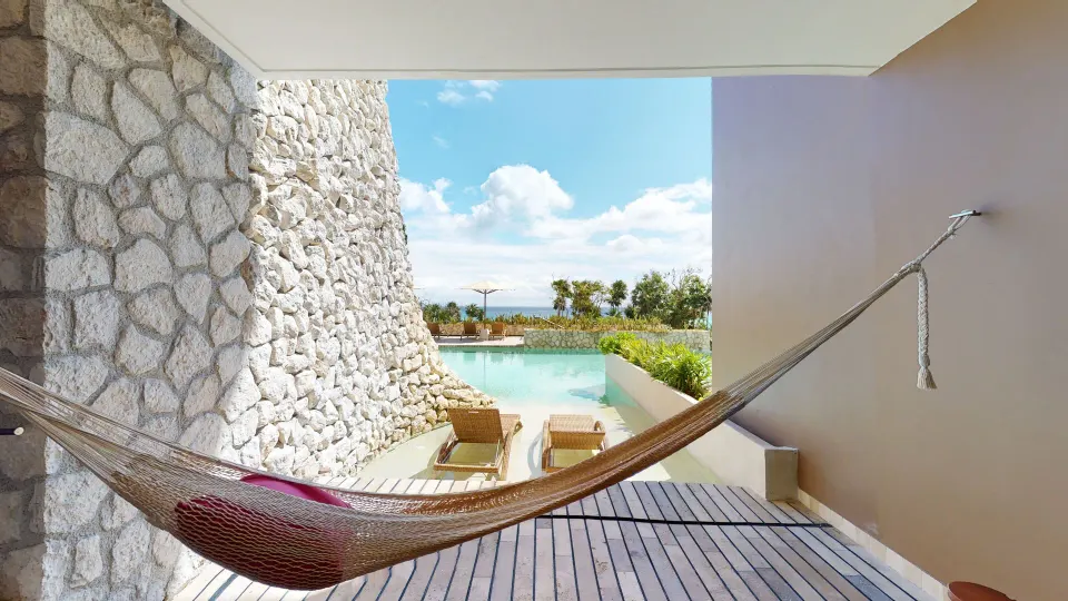 Private terrace with hammock and swim-up pool by an Oceanfront Swim Up room at Hotel Xcaret Arte.
