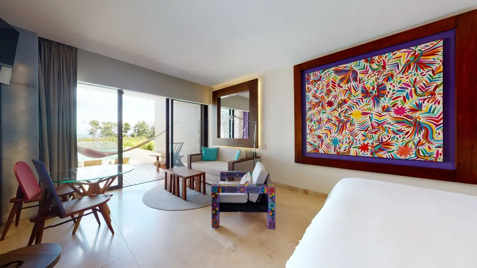 Oceanfront Swim Up room with king bed, colorful wall art, and terrace at Hotel Xcaret Arte.