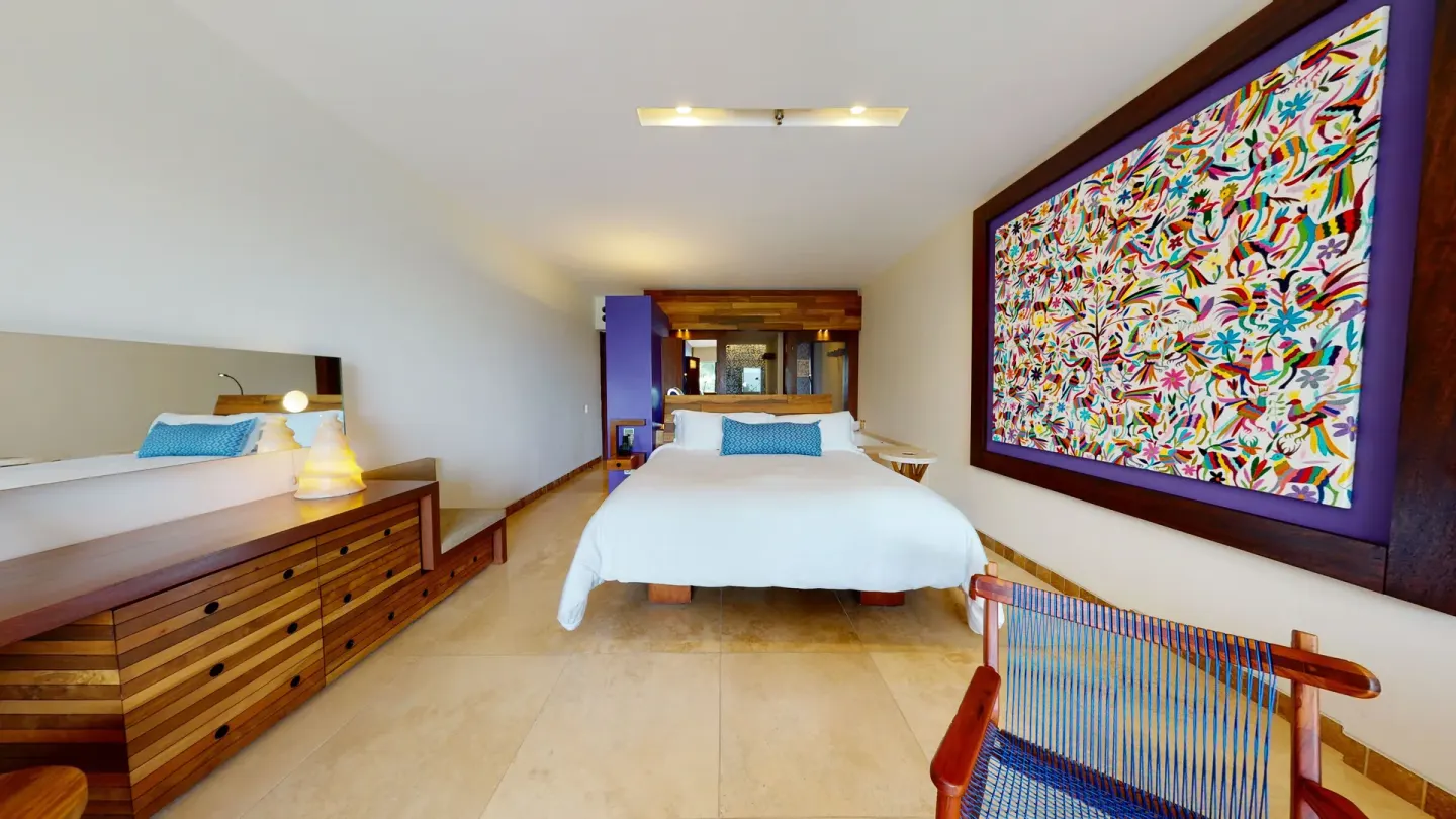 Oceanfront guest room with king bed and colorful wall art at Hotel Xcaret Arte.