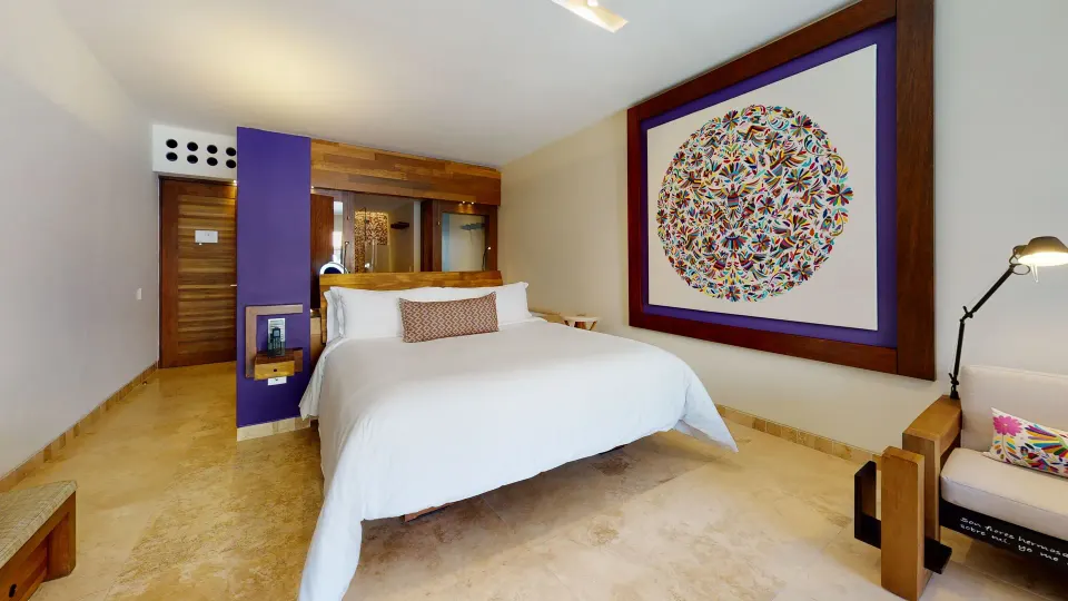Suite Garden Spa king bed with large colorful wall art at Hotel Xcaret Arte.