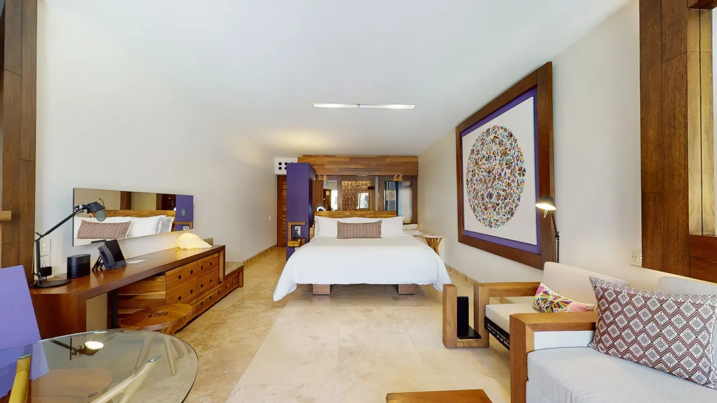 Suite Garden Spa guest room with king bed, sofa and desk at Hotel Xcaret Arte.