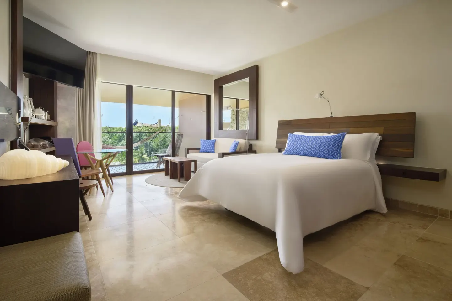 Garden suite with king bed, seating area, and balcony at Hotel Xcaret Arte.