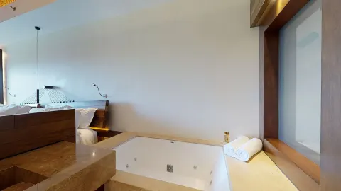 Garden suite soaking tub beside the bed and window at Hotel Xcaret Arte.