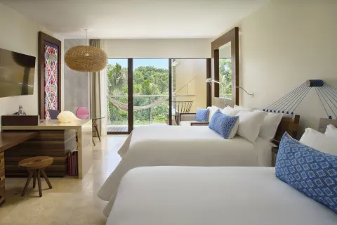 Suite garden with two beds, balcony hammock and greenery at Hotel Xcaret Arte.