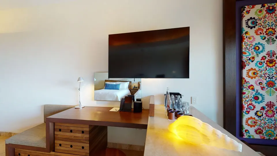 Suite garden workspace with desk, TV and colorful wall art at Hotel Xcaret Arte.
