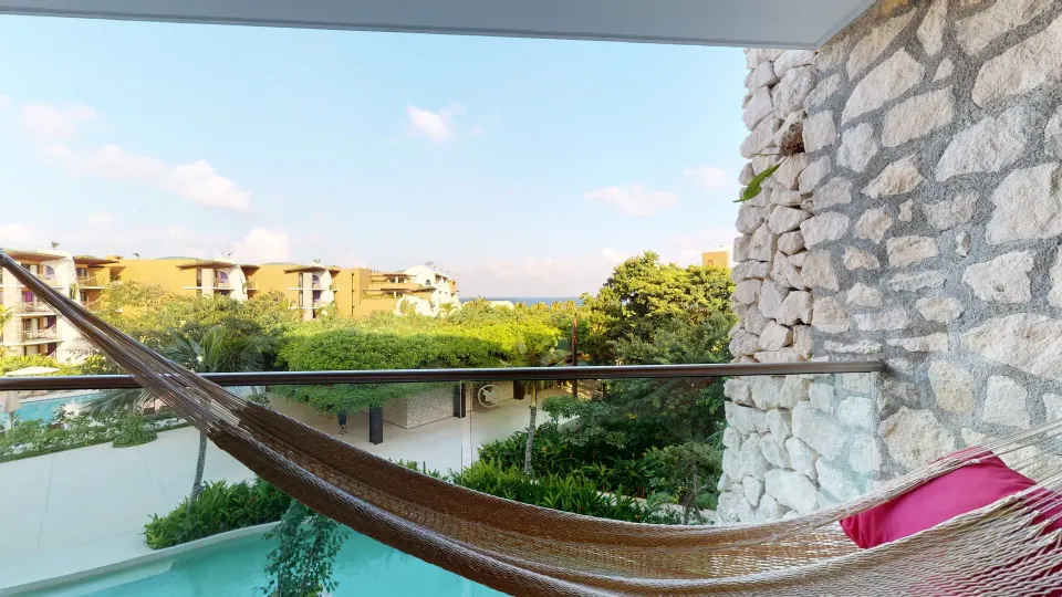 Ocean View Suite balcony hammock with greenery and ocean in the distance at Hotel Xcaret Arte.