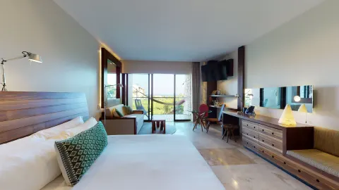 Suite Ocean View room with king bed, sitting area, desk, and balcony at Hotel Xcaret Arte.