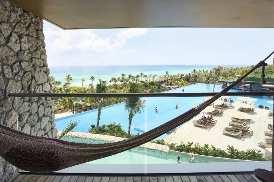Suite Oceanfront King balcony view of pools and ocean at Hotel Xcaret Arte.