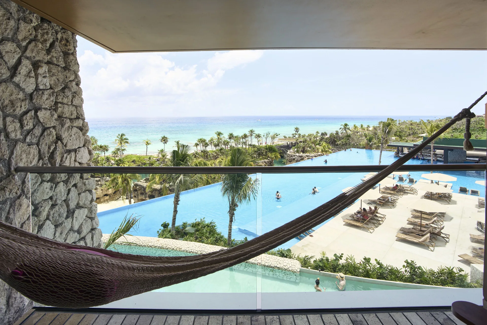 Suite Oceanfront King balcony view of pools and ocean at Hotel Xcaret Arte.
