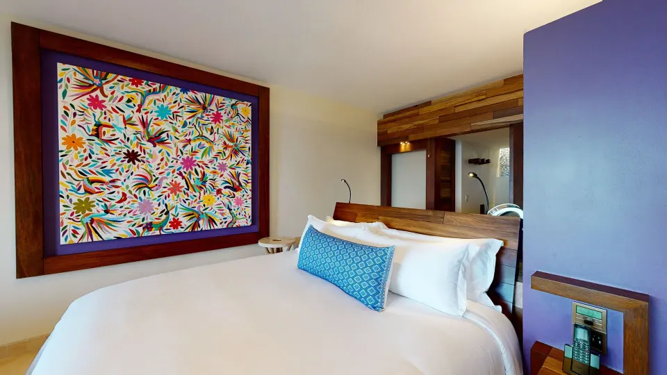 Suite Oceanfront King bed with colorful wall art at Hotel Xcaret Arte.