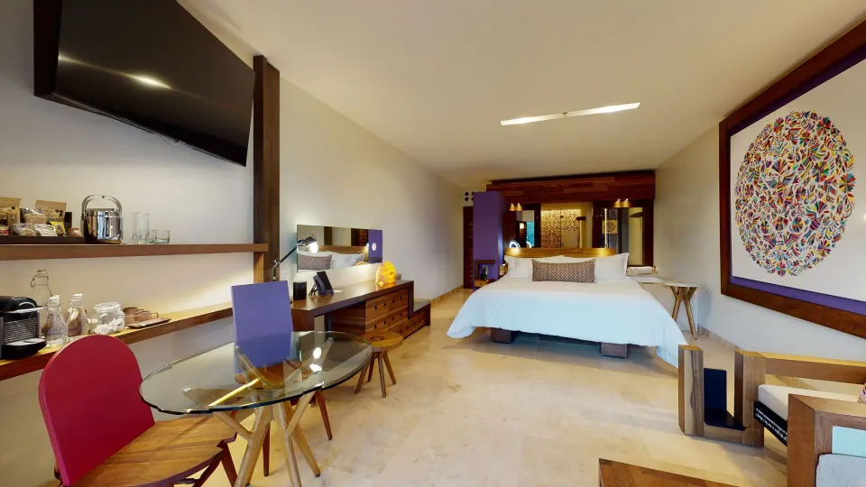 Suite River Spa king bed with desk, dining table, and TV at Hotel Xcaret Arte.