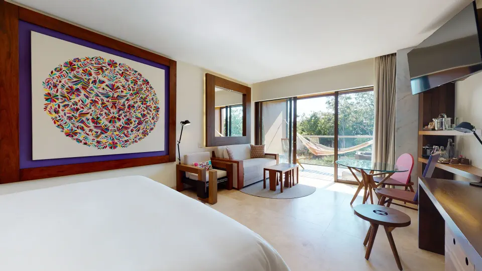 Suite River Spa sitting area, king bed, and balcony at Hotel Xcaret Arte.