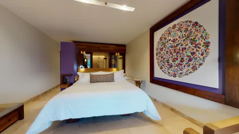 Suite River Spa king bed with colorful wall art at Hotel Xcaret Arte.