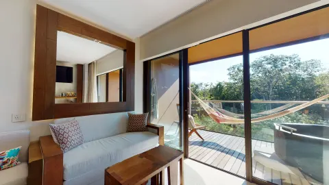 Suite River Spa sofa by balcony with hammock and outdoor tub at Hotel Xcaret Arte.