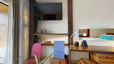 Suite River View Jump Adults desk, TV, minibar shelves, and bed reflection at Hotel Xcaret Arte.