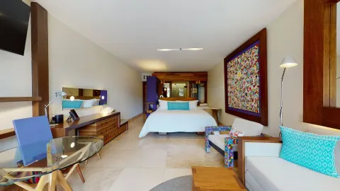 Suite River View Jump Adults guest room with king bed and seating at Hotel Xcaret Arte.