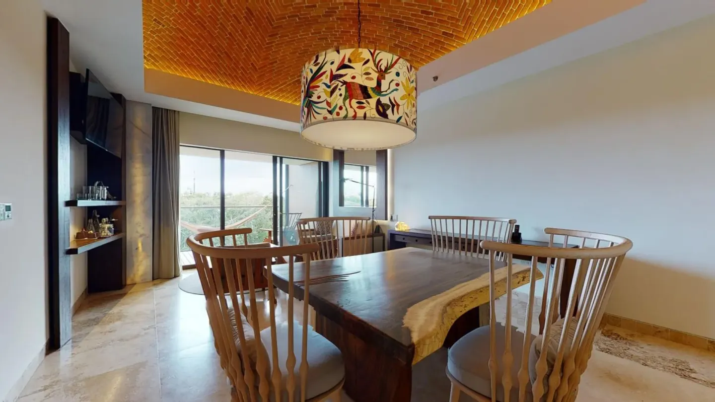 River View suite dining area with wooden table, chairs, and balcony at Hotel Xcaret Arte.