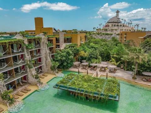 Aerial view of pools, terraces, and stone guest room buildings at Hotel Xcaret Mexico.