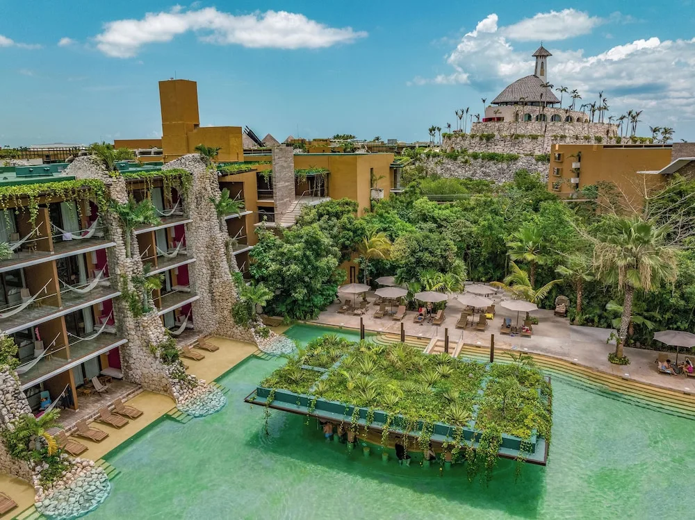 Aerial view of pools, terraces, and stone guest room buildings at Hotel Xcaret Mexico.