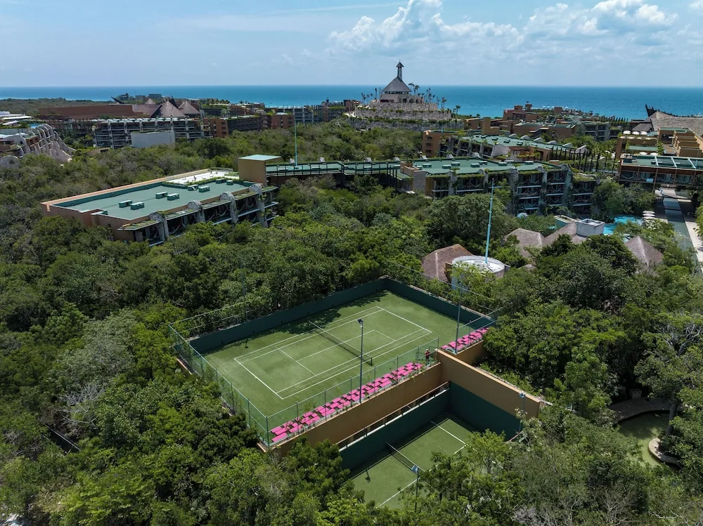 An aerial view of tennis courts, resort buildings and the sea at Hotel Xcaret Mexico.
