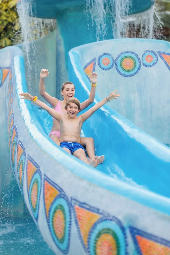 Two children riding a blue waterslide at Hotel Xcaret Mexico.