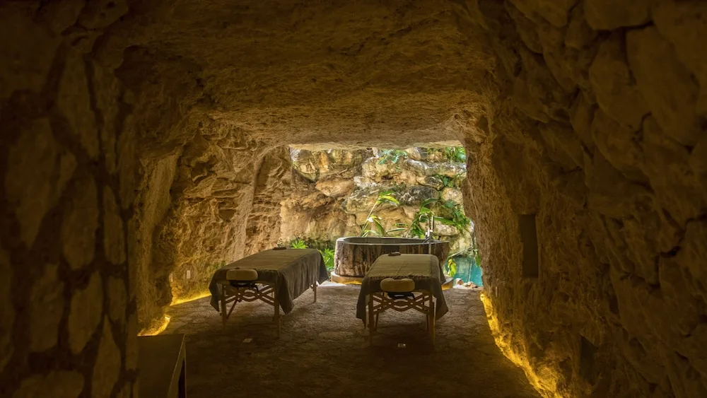 Cave spa treatment area with two tables and a soaking tub at Hotel Xcaret Mexico.