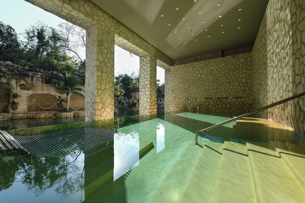 Covered pool with stone columns and lagoon views at Hotel Xcaret Mexico.