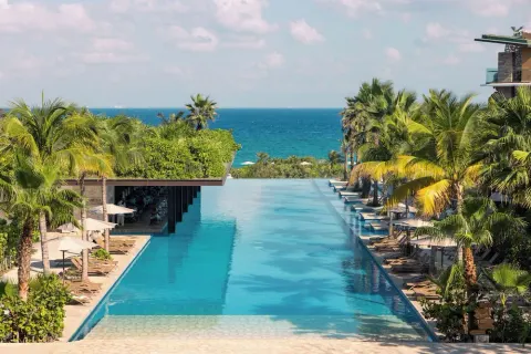 Infinity pool with palm trees and ocean view at Hotel Xcaret Mexico.