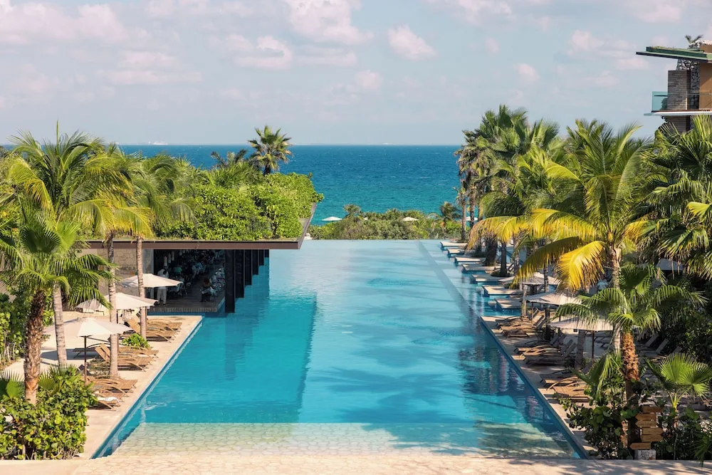 Infinity pool with palm trees and ocean view at Hotel Xcaret Mexico.