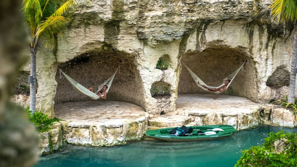 Hammocks hang in limestone alcoves beside water at Hotel Xcaret Mexico.