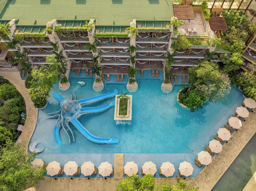 Aerial view of a blue pool with an octopus slide and lounge umbrellas at Hotel Xcaret Mexico.