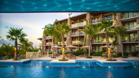 Poolside guest room buildings with palms and balconies at Hotel Xcaret Mexico.