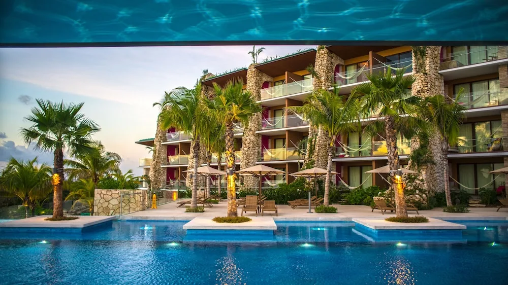 Poolside guest room buildings with palms and balconies at Hotel Xcaret Mexico.
