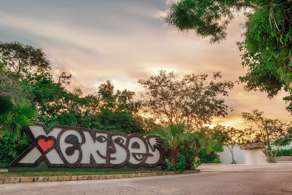 Large Xcaret sign surrounded by tropical plants at sunset at Hotel Xcaret Mexico.
