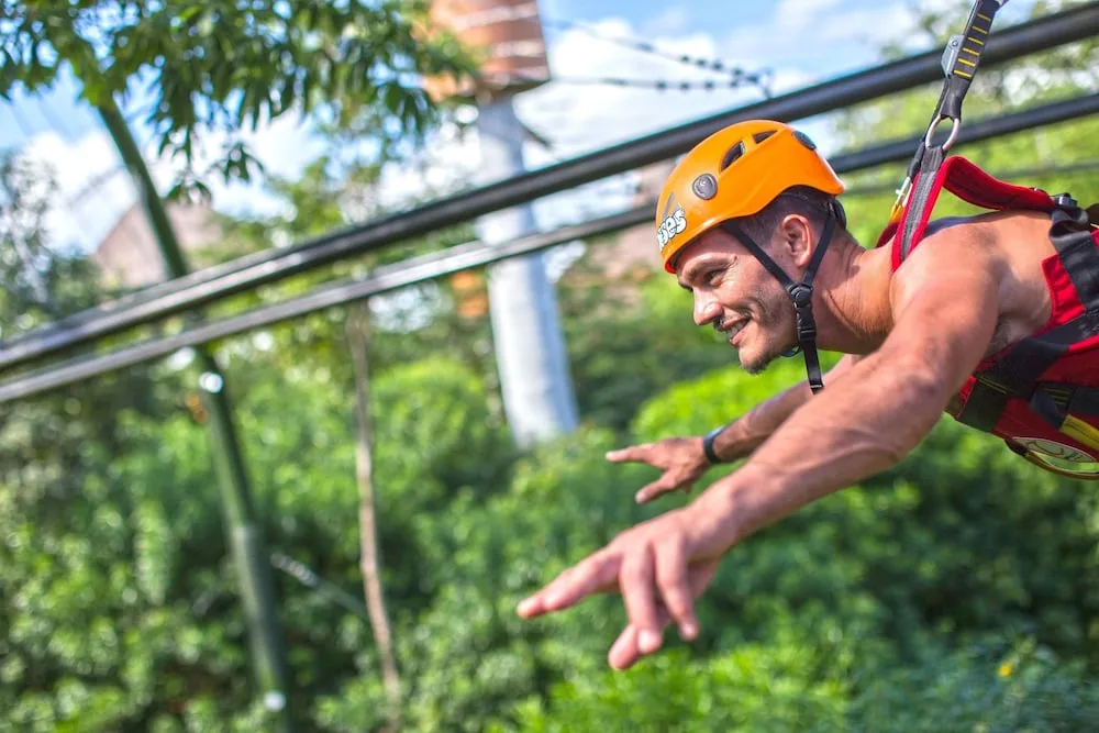 A helmeted guest rides a zipline near Hotel Xcaret Mexico.