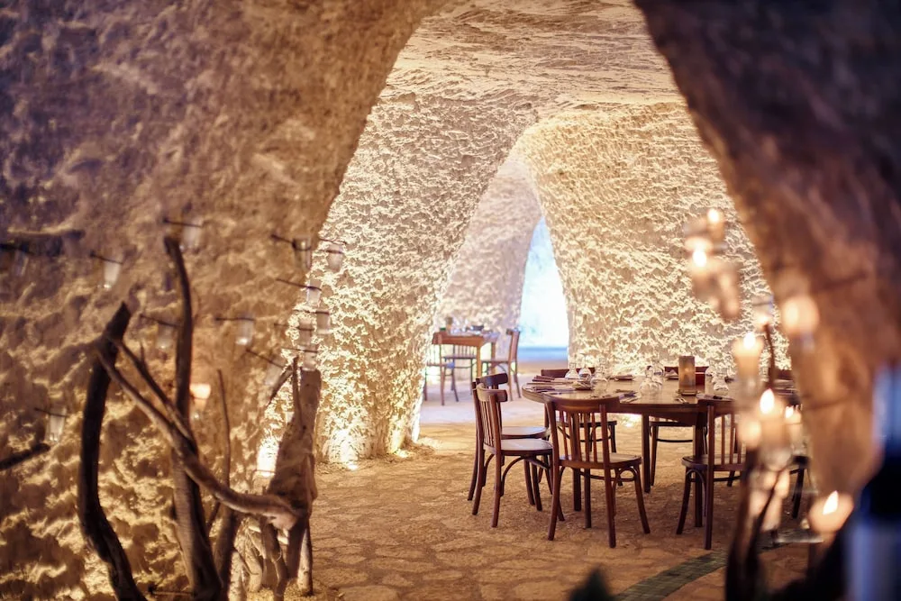 Cave-like dining room with arched stone walls and set tables at Hotel Xcaret Mexico.