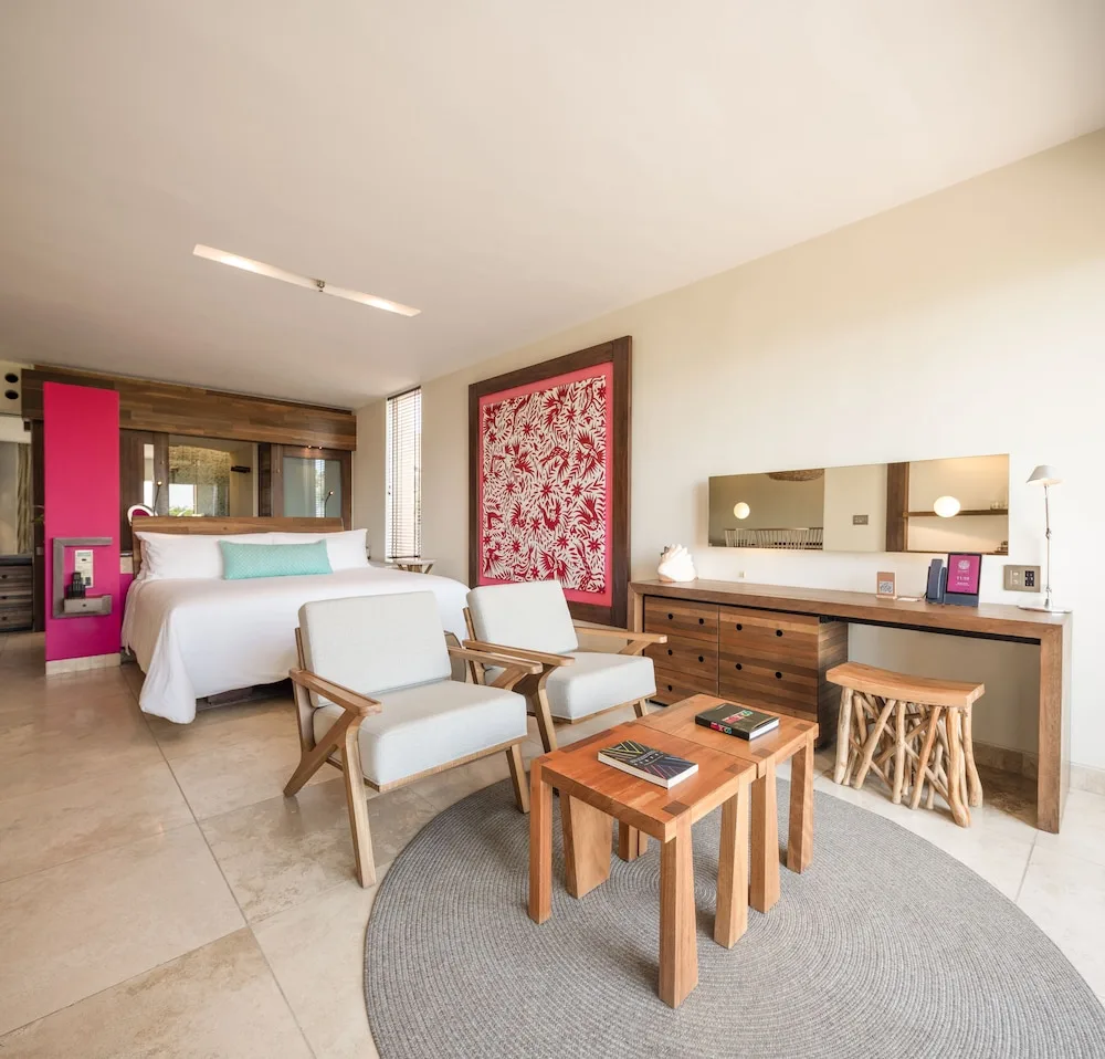 Junior Suite Adults Only guest room with king bed and sitting area at Hotel Xcaret Mexico.