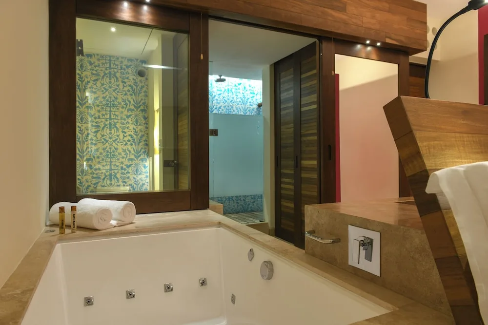 Suite Garden bathroom tub with shower area and blue patterned tile at Hotel Xcaret Mexico.